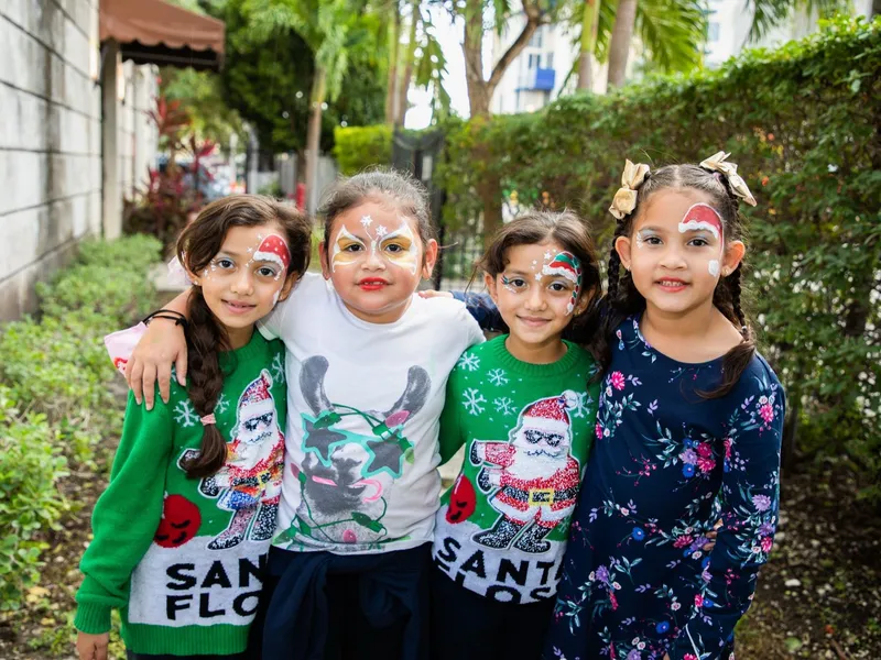 Four students with painted faces smile together outside the center.