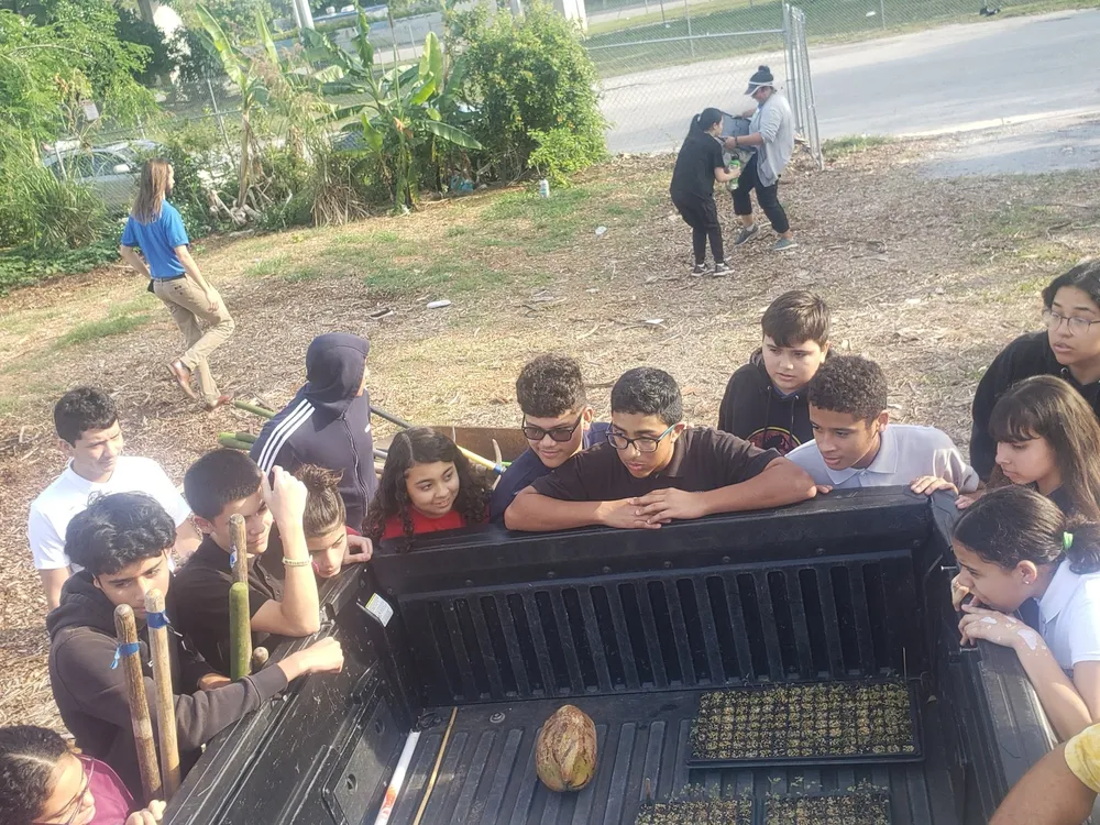 Students and staff gather around a truck bed full of harvested produce from the garden.