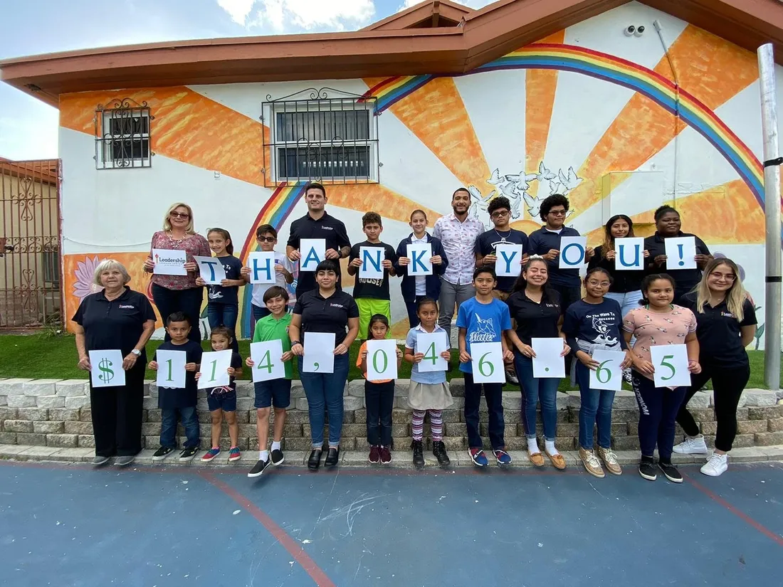 Students on the court hold letter cards spelling “Give Miami Day, thank you!”