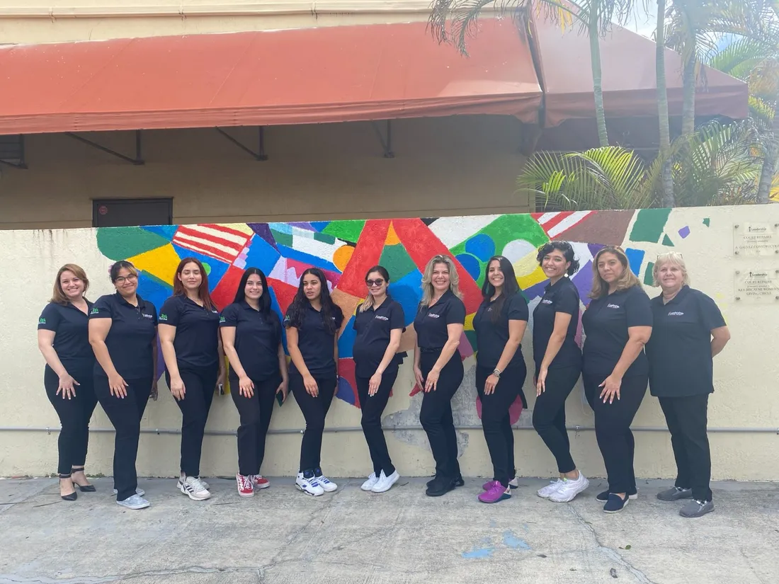 The Leadership Learning Center staff team stands together in front of the colorful mural.