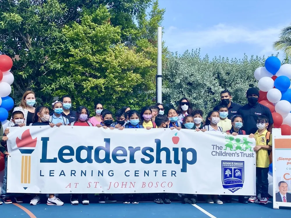Campers and staff pose behind a Leadership Learning Center banner with balloons.